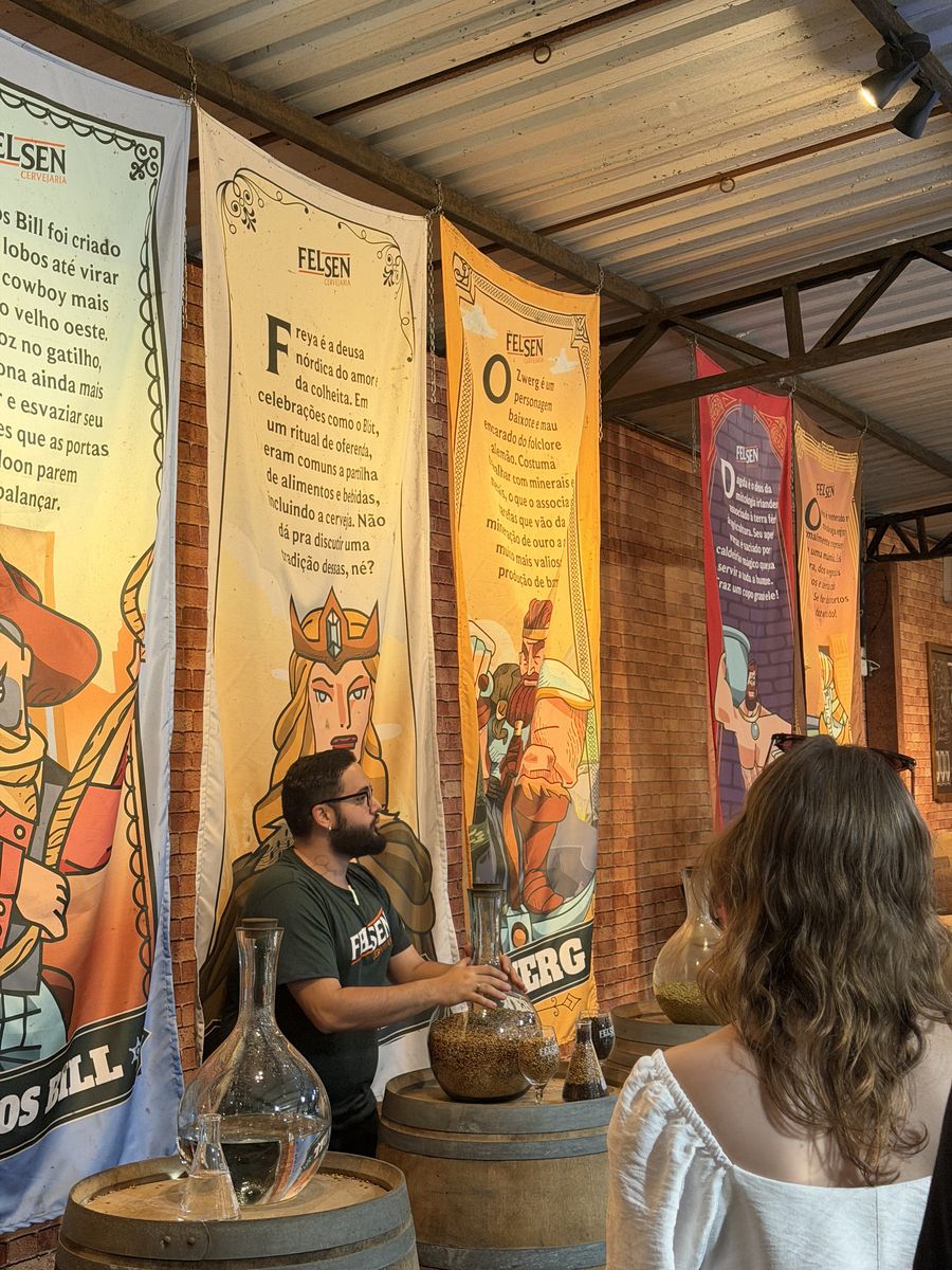 Guia do Felsen Beer Tour conversa com visitantes entre barris e estandartes ilustrados