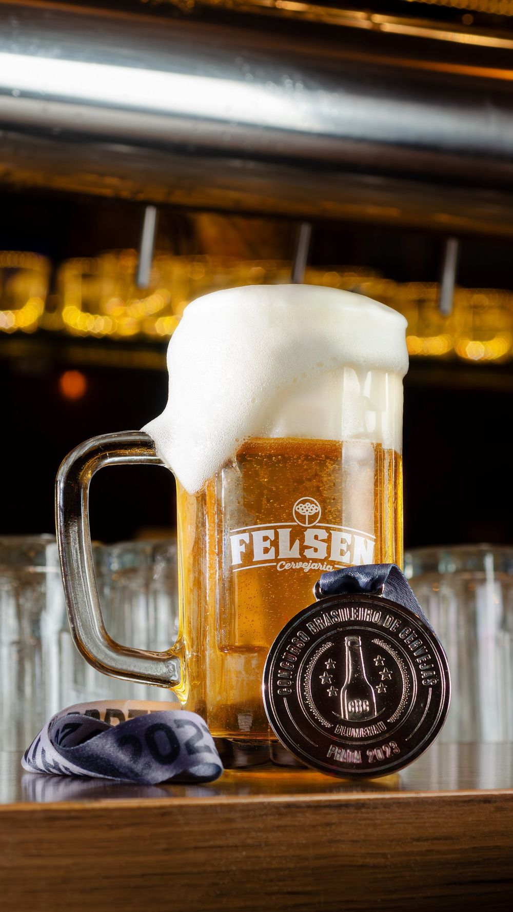 Caneca de chope Felsen com espuma ao lado da medalha de prata do Concurso Brasileiro de Cervejas 2023